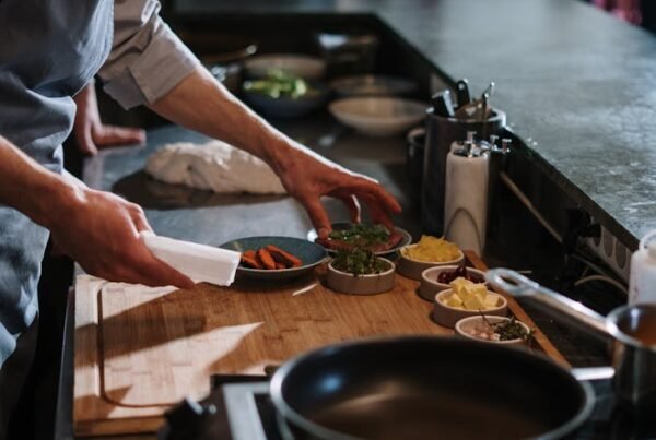 Person in White Apron Holding White Ceramic Plate